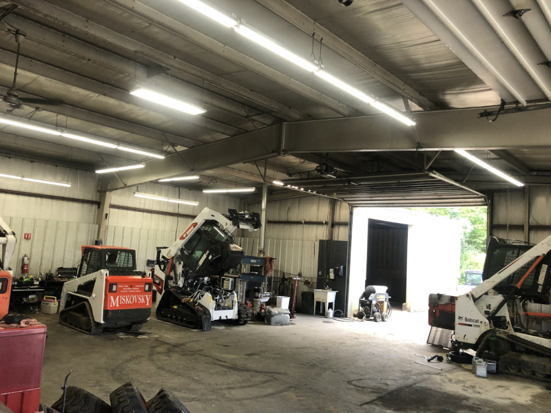 Various types of heavy equipment parked inside a warehouse.